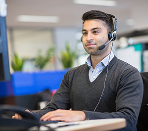 Man working at a computer, wearing a head set. 