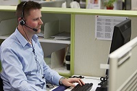 Man working at a computer with a headset on. 