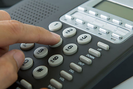 fingers pressing buttons on a land line phone.