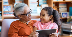 Grandmother and child looking at digital tablet in a lounge room